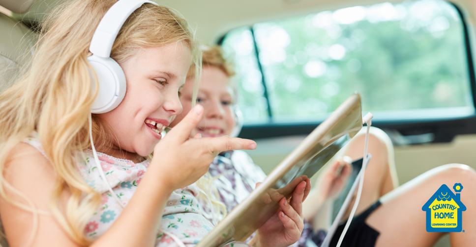 kids in a car listening to a tablet through headphones