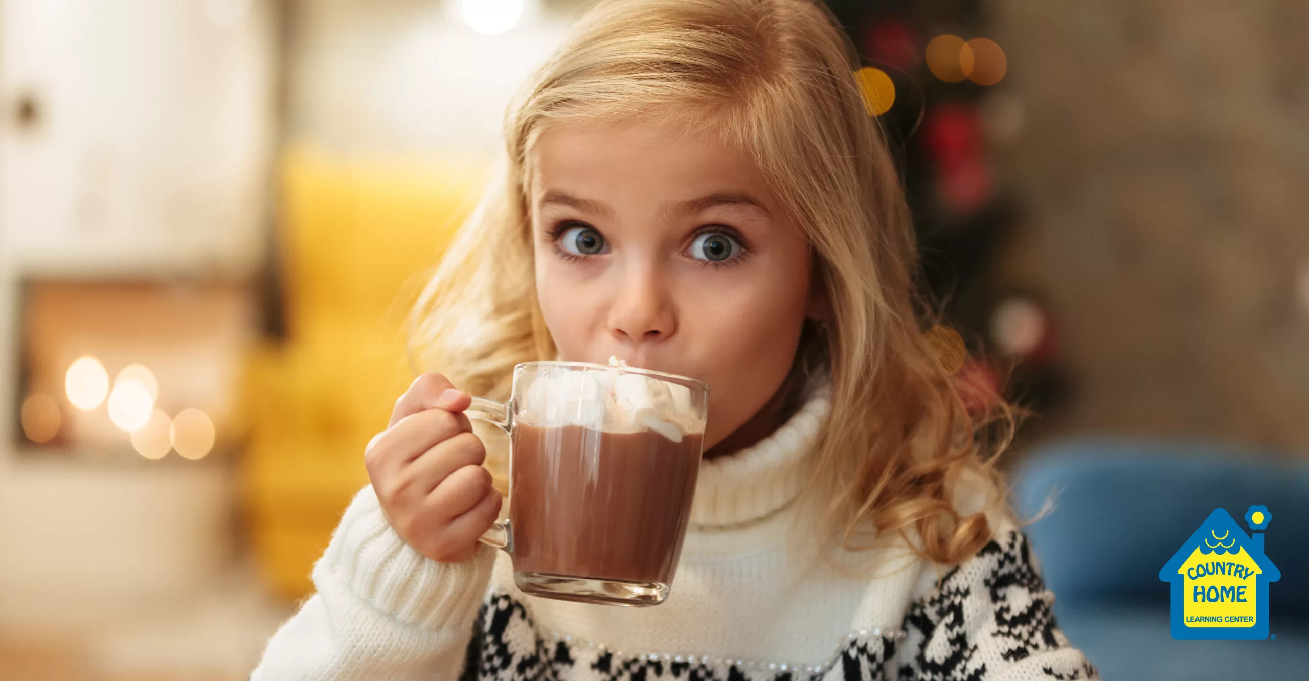 blonde girl drinking hot chocolate in a mug in front of a christmas tree