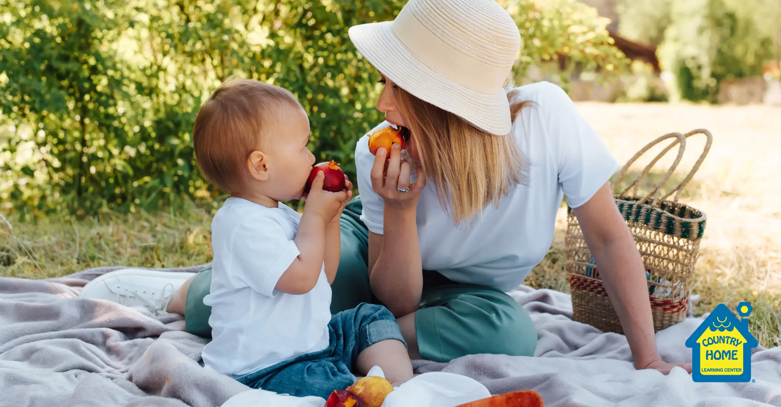 young mom and toddler eating peaches during an outdoor picnic