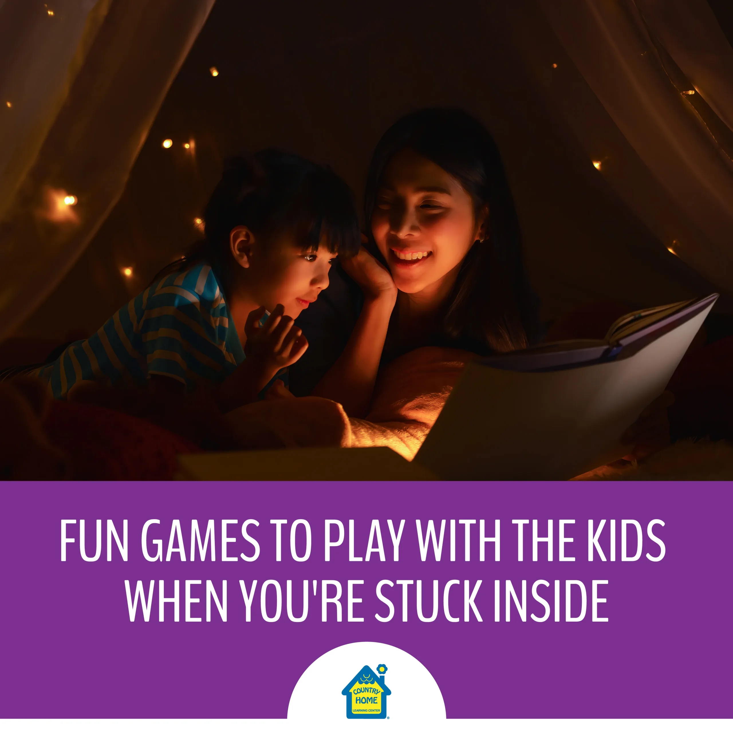 asian mother and daughter spend quality time together inside on a rainy day while reading a book in a tent under twinkly lights