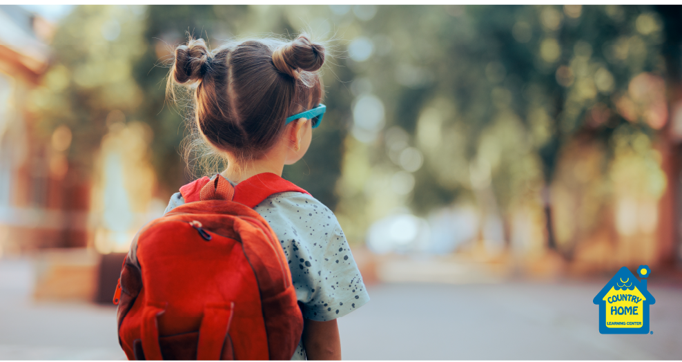 Young girl wearing red backpack staring down the street, ready for daycare.