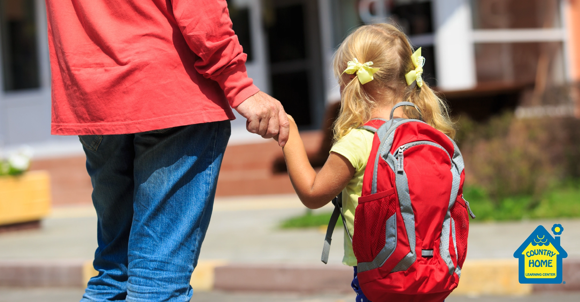 Parent holding little girls hand walking into daycare
