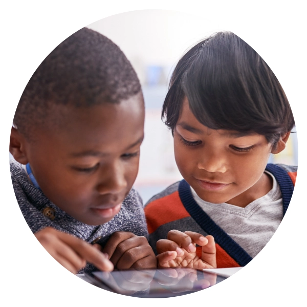 Two young children play an educational game on an iPad.