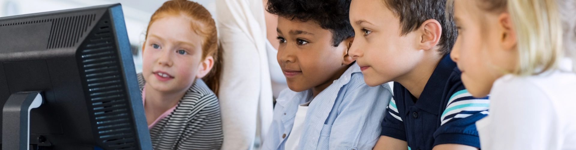 Young children at school, looking at educational resources on a computer.