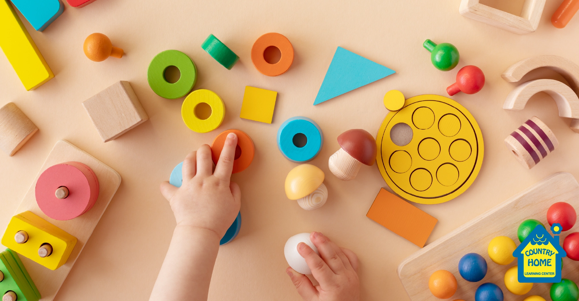 Toddler hands with colorful wooden toys on table from above