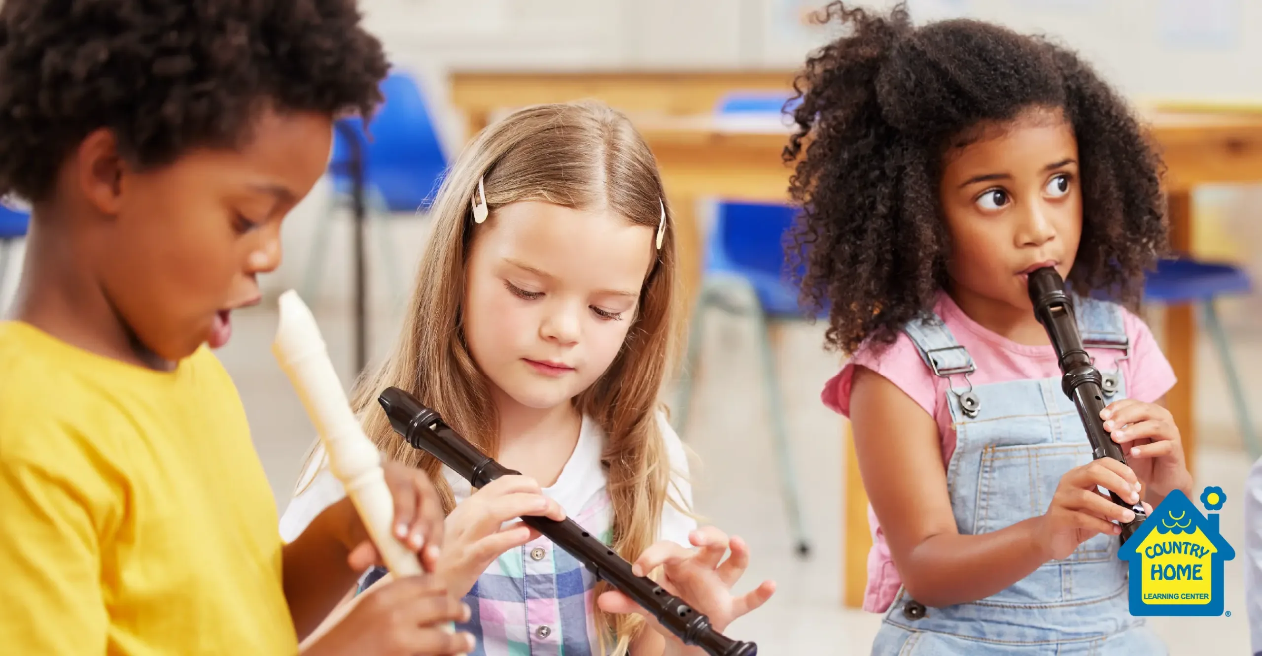 Three young children developing focus and coordination skills in the classroom by playing recorders.