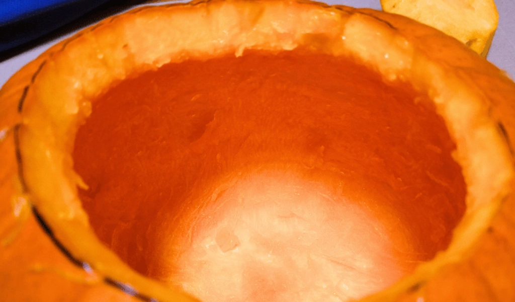 Close-up of the inside of a hollowed-out pumpkin with the top cut off, showing the smooth orange interior.