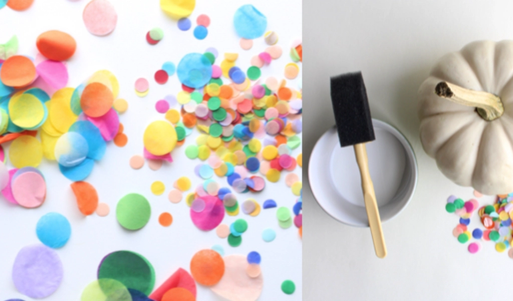 Colorful confetti scattered on a white surface next to a white pumpkin, a foam brush, a bowl, and more confetti arranged for a craft project.