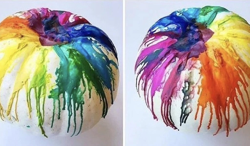 White pumpkins with melted crayon wax in various colors dripping down from the tops, creating a rainbow effect on each pumpkin.