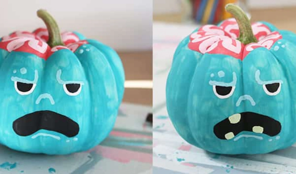 Two teal pumpkins with painted angry faces