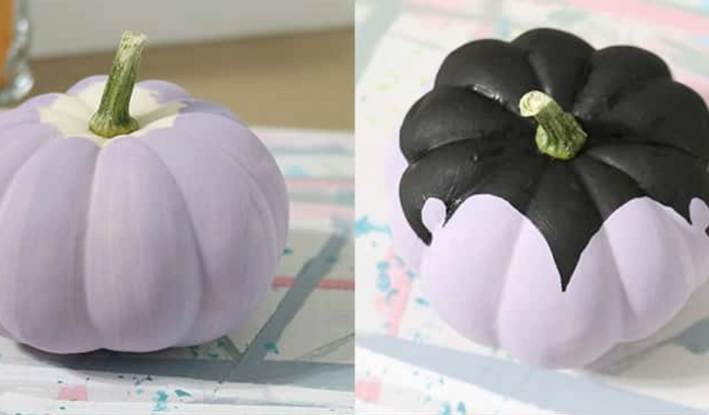Two small pumpkins painted lavender, with one pumpkin having black paint covering, showing step-by-step how to paint a vampire