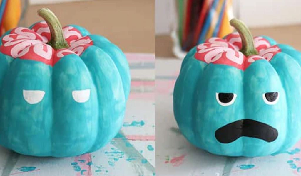 Two teal-painted pumpkins showing you step-by-step how to paint a zombie face