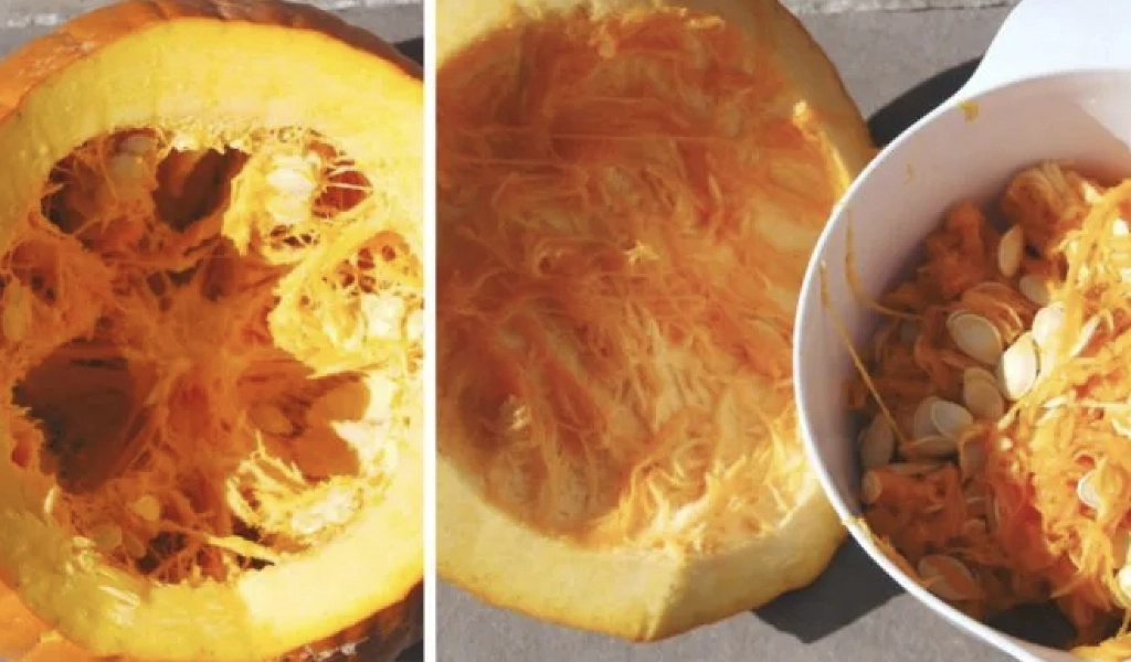 A pumpkin cut open showing its interior, with one half placed next to a bowl containing pumpkin seeds and stringy flesh.