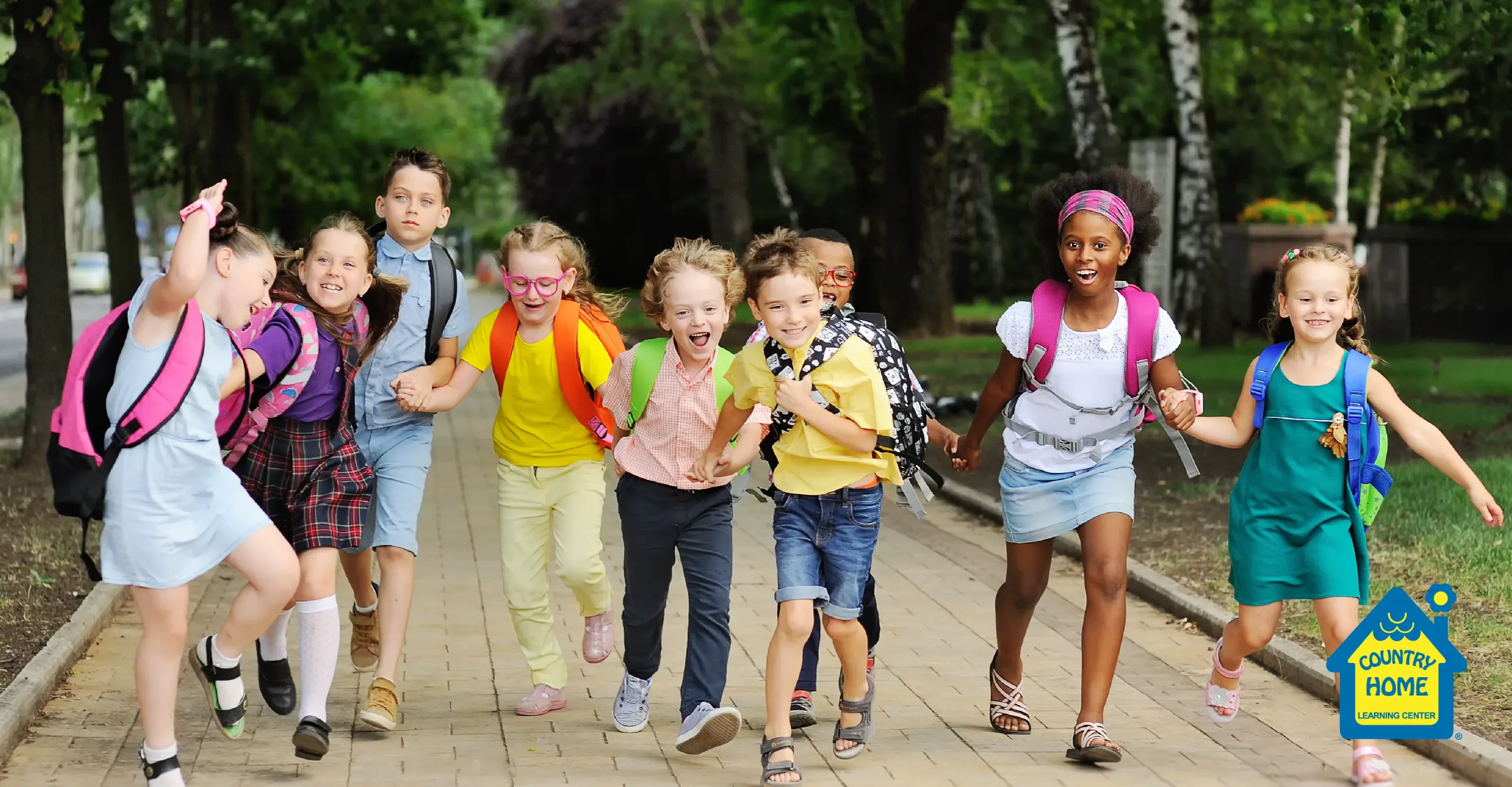 Group of young children with backpacks running together and laughing on a school walkway