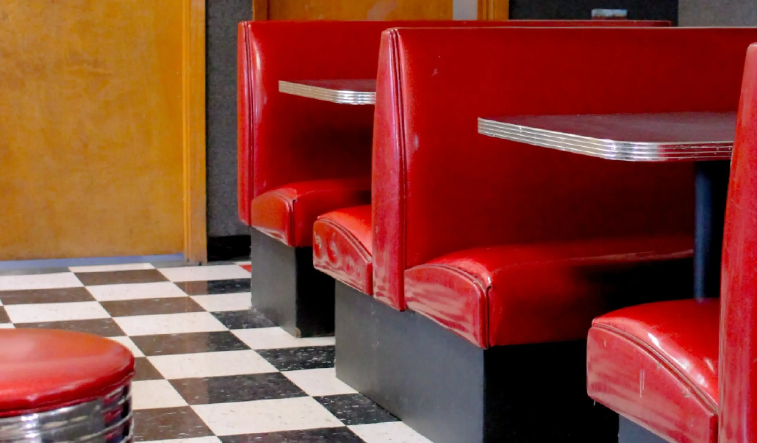 Red vinyl booths with a black and white checkerboard floor in a daycare cafe space