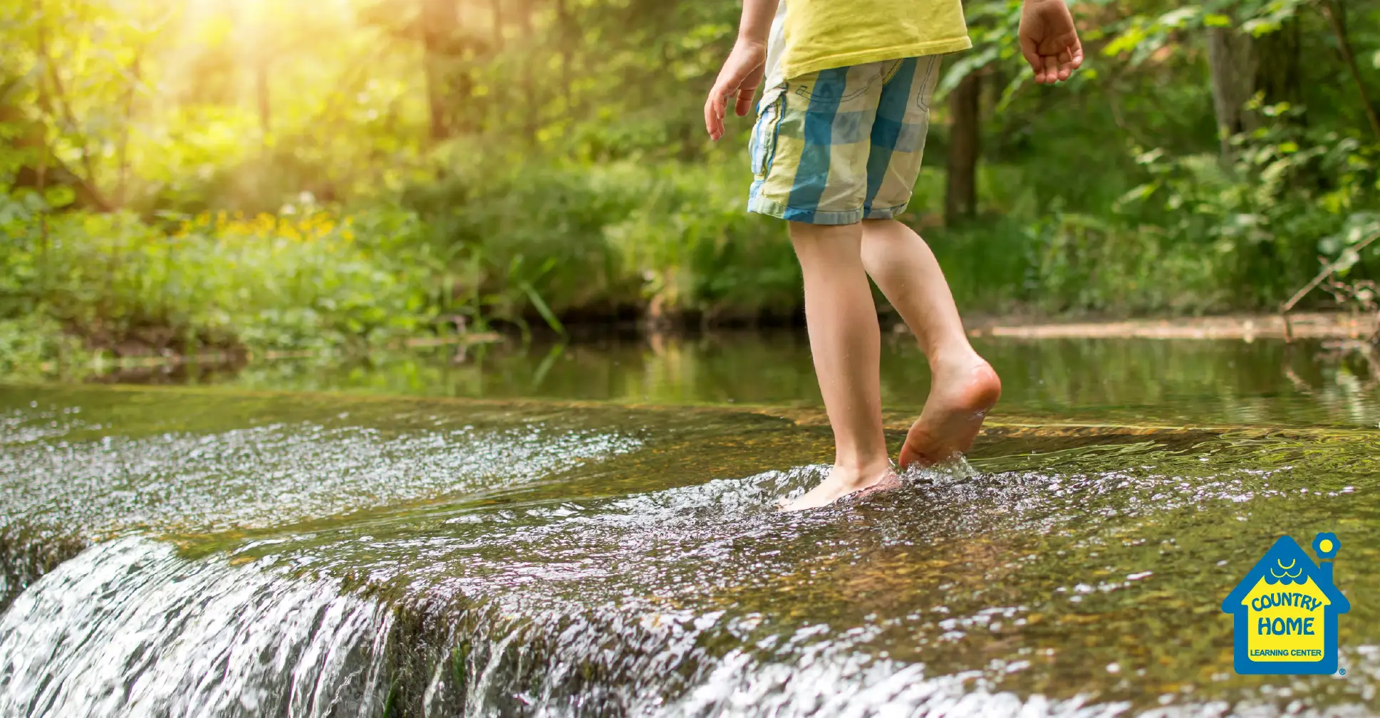 A kid walking in a creek with bare feet.