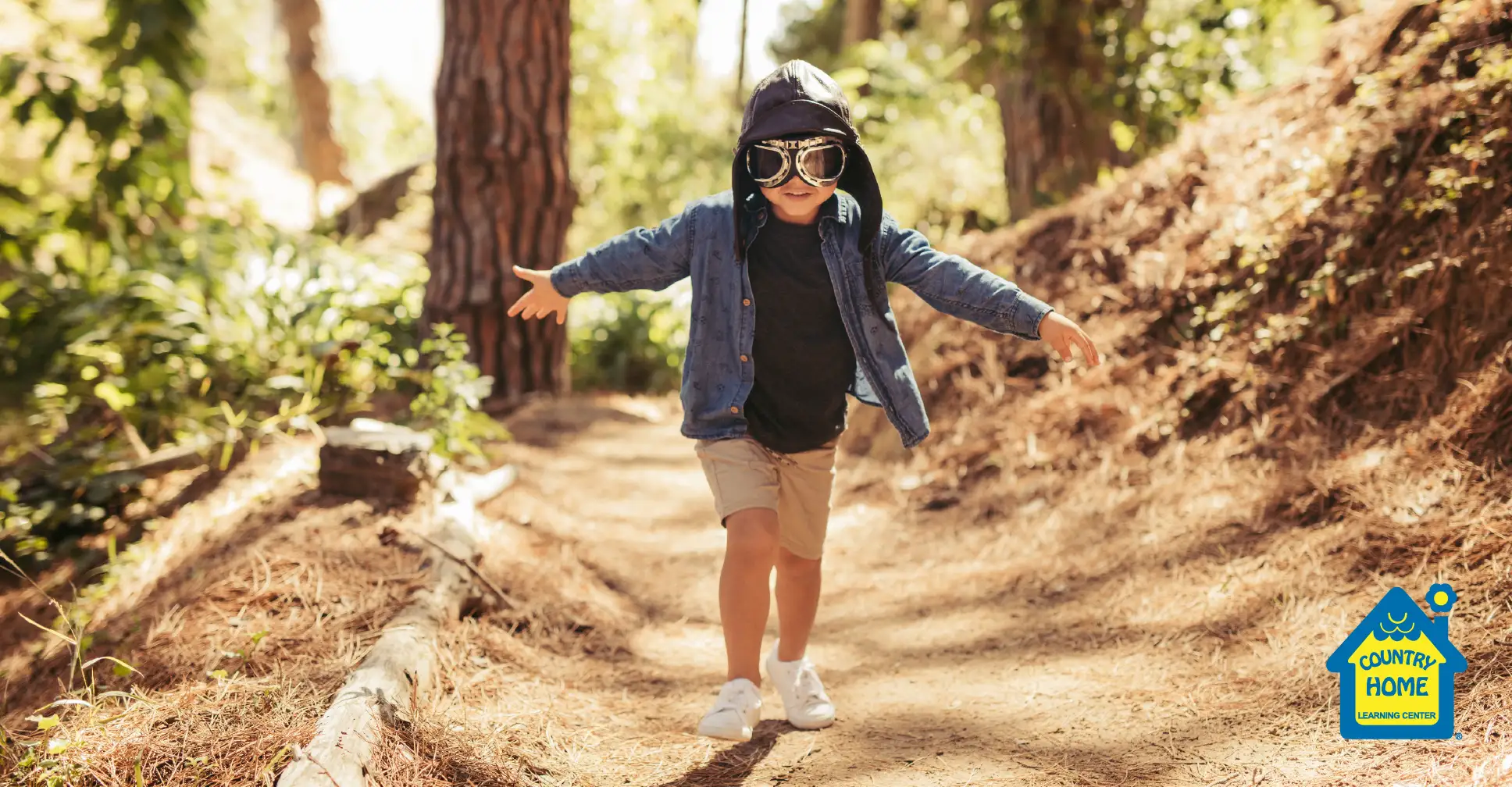 Boy pretending to be a pilot on a path in the woods.