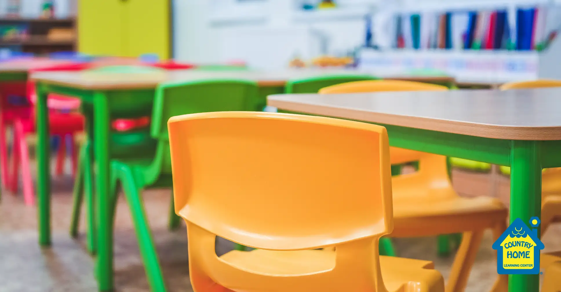 Classroom for preschoolers with desks and colorful chairs.